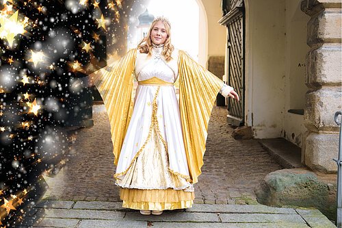 Christkind im goldenen Gewand mit Sternenhintergrund Das Christkind steht im Torbogen des Stadtschlosses und breitet seine Arme aus. So sieht man die Flügel des prächtigen goldenen Gewandes.